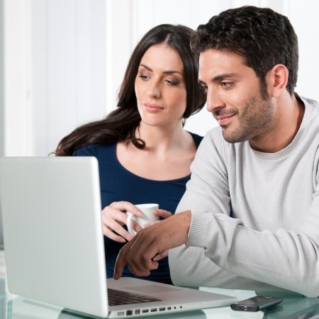 Couple on the computer talking about the 12 topics that are the most important to talk about before getting married.