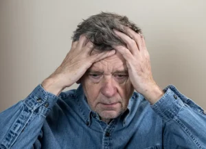 Older adult holding their head with a distressed expression illustrating dealing with troubled times and emotional stress