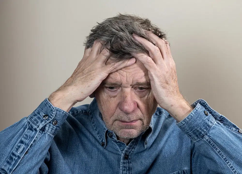 Older adult holding their head with a distressed expression illustrating dealing with troubled times and emotional stress
